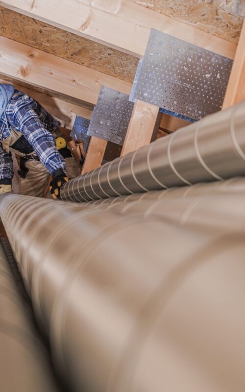 Residential Air Ventilation Pipeline Building. Worker Preparing Metal Air Vent Pipes.