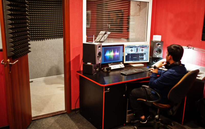 Young asian singer with microphone recording song in record music studio with sound producer.