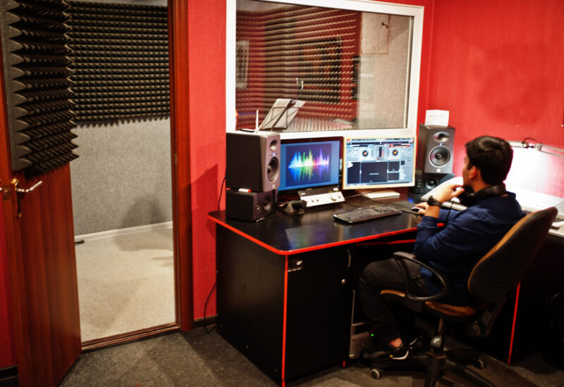 Young asian singer with microphone recording song in record music studio with sound producer.